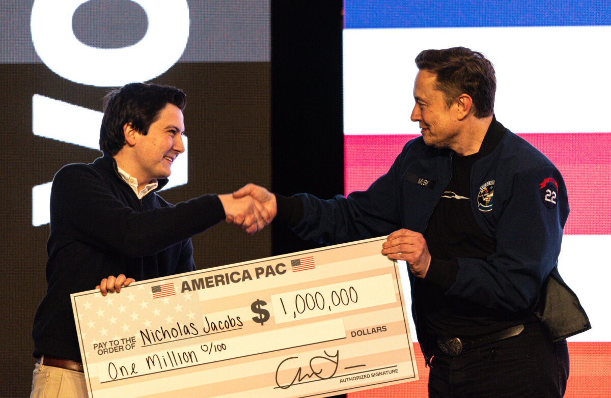 Elon Musk hands over a million dollar check to Nicholas Jacobs during a town hall in Green Bay, Wis., on March 30, 2025. (Jeffrey Phelps/AP Photo)
