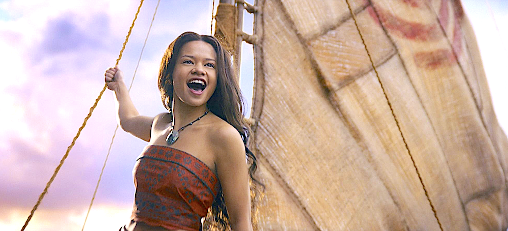 young woman in red stands on raft with sail in Moana
