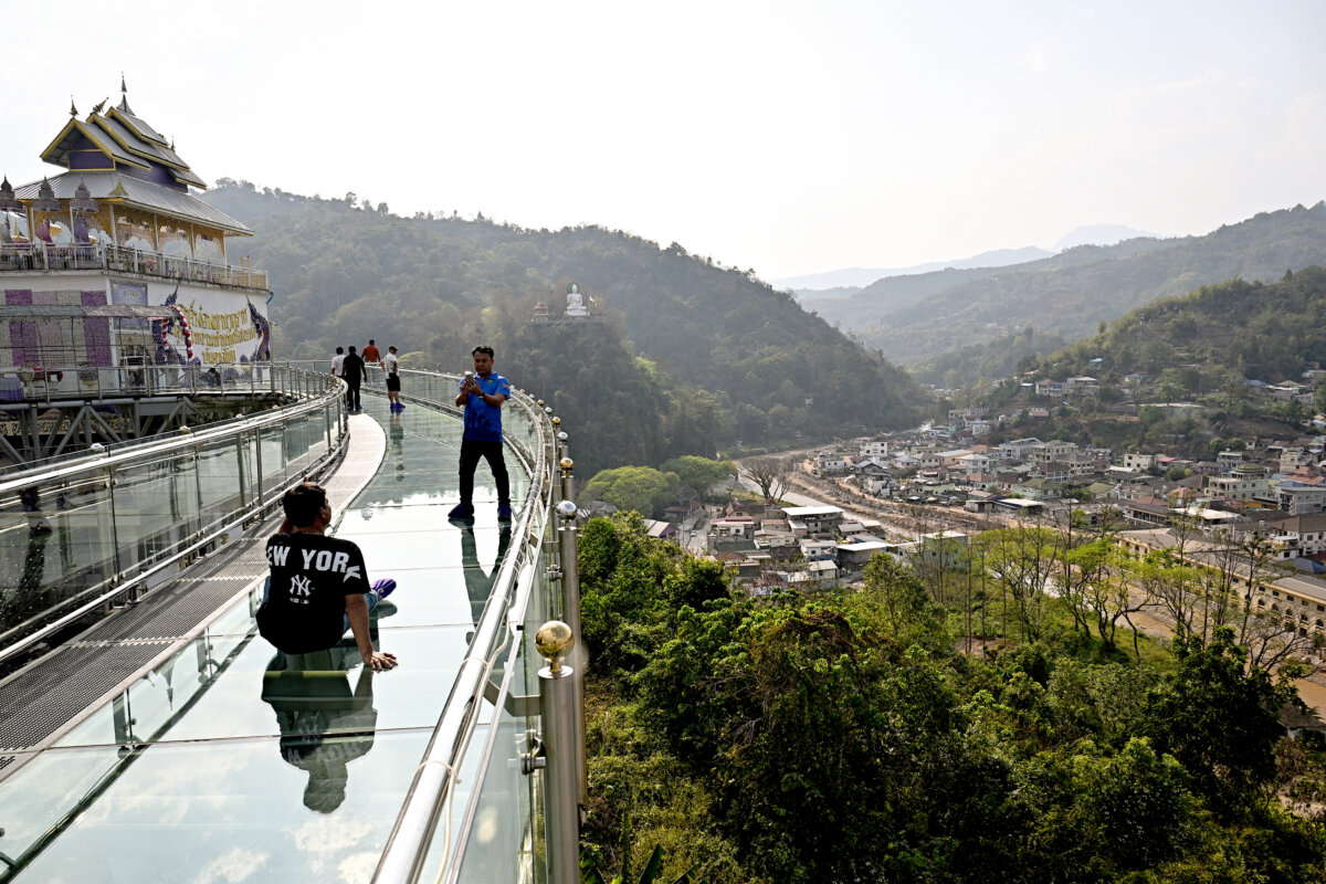 Visitors walk on a skybridge overlooking Myanmar's border town of Tachileik (R) at Wat Phra That Doi Wao Buddhist temple in Mae Sai in the northern Thai province of Chiang Rai on March 17, 2026. (Lillian Suwanrumpha/AFP/Getty Images/TNS)