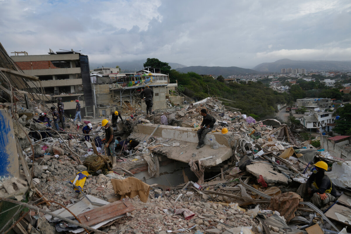 Rescue workers search through the rubble oa a building collapsed during the earthquakes in La Guaira, Venezuela, on July 6, 2026. (AP Photo/Ariana Cubillos)