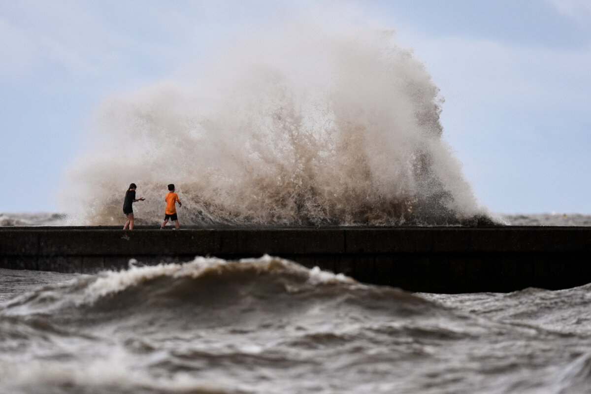 Children play near breaking waves on West End Pier on Lake Pontchartrain as Tropical Storm Bertha approaches the Louisiana Coast, in New Orleans on July 22, 2026. (Gerald Herbert/AP Photo)