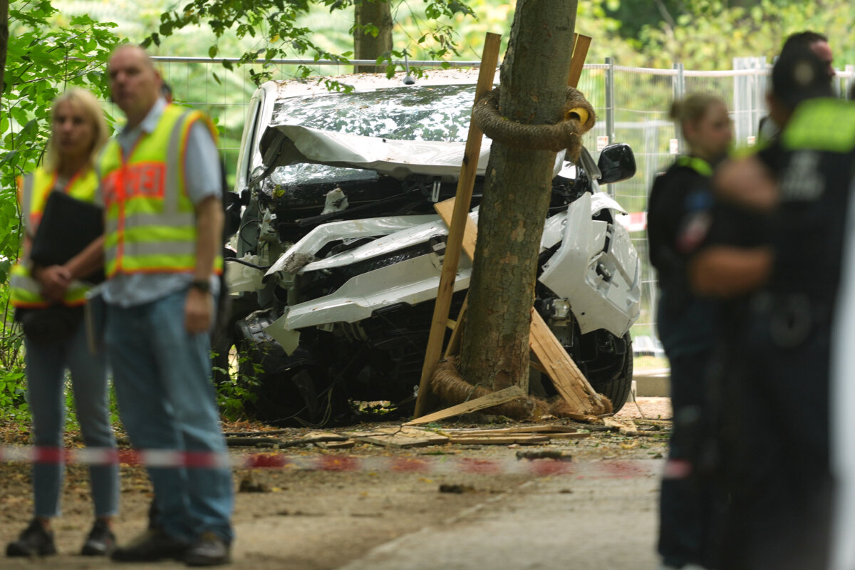 Police officers stand near a vehicle crashed into a tree after it was driven into a crowd near an annual Pride event, in Berlin on July 26, 2026. (AP Photo/Markus Schreiber)