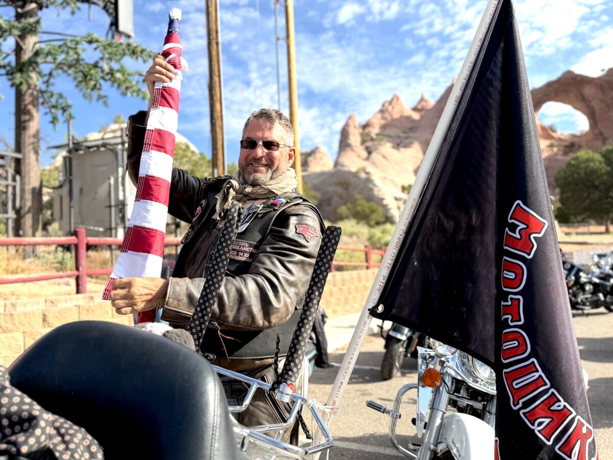 A Nation of Patriots rider removes the U.S. flag from the back of a motorcycle in the Navajo Nation's capital of Window Rock, Ariz., on July 28, 2026. (Allan Stein/The Epoch Times)