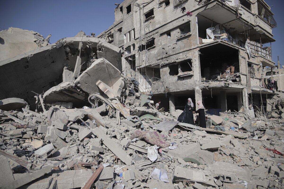 A Palestinian woman walks through rubble beside a collapsed residential building after an Israeli airstrike in the Al-Nasr neighborhood of western Gaza City on July 30, 2026. (Mohammed M Skaik/Middle East Images via AFP via Getty Images)