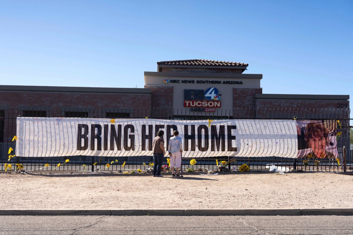 People visit a banner for Nancy Guthrie, the missing mother of "Today" show host Savannah Guthrie, outside the KVOA Newsroom in Tucson, Ariz., on March 6, 2026. (AP Photo/Rebecca Noble)