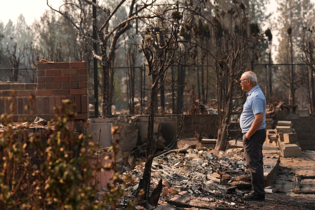 Daniel Sim, 76, views the remains of his destroyed house after a wildfire hit the northern part of Spokane, Wash., on Aug. 3, 2026. (AP Photo/Lindsey Wasson)