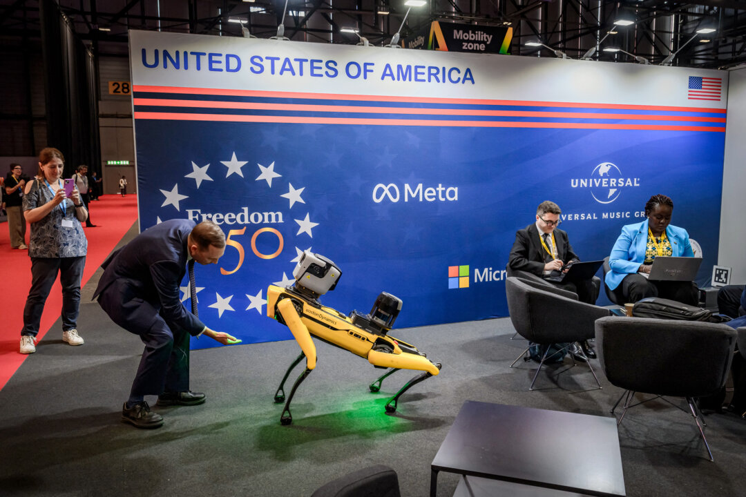 Посетитель взаимодействует с роботом, похожим на собаку, от компании Boston Dynamics в павильоне США во время Глобального саммита по искусственному интеллекту во благо в Женеве 7 июля 2026 года. (Fabrice Coffrini/AFP via Getty Images)