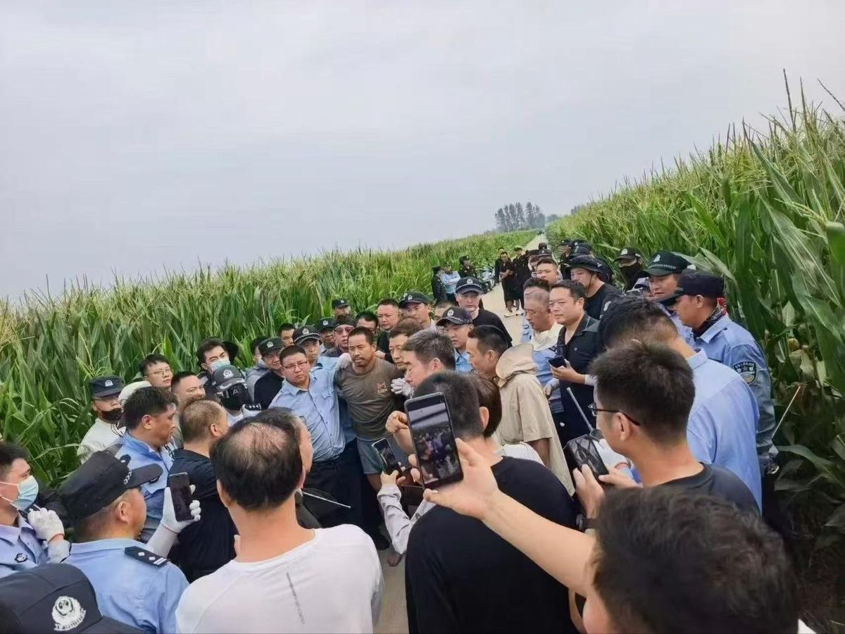 Xia Fugang (the man with a beard wearing a grey T shirt in the center of the photo, grabbed by the collar by a police officer with glasses) is arrested by police in Kongzhongguo Town, Luohe City, Henan, China, on Aug. 8, 2026. (Courtesy of interviewee)