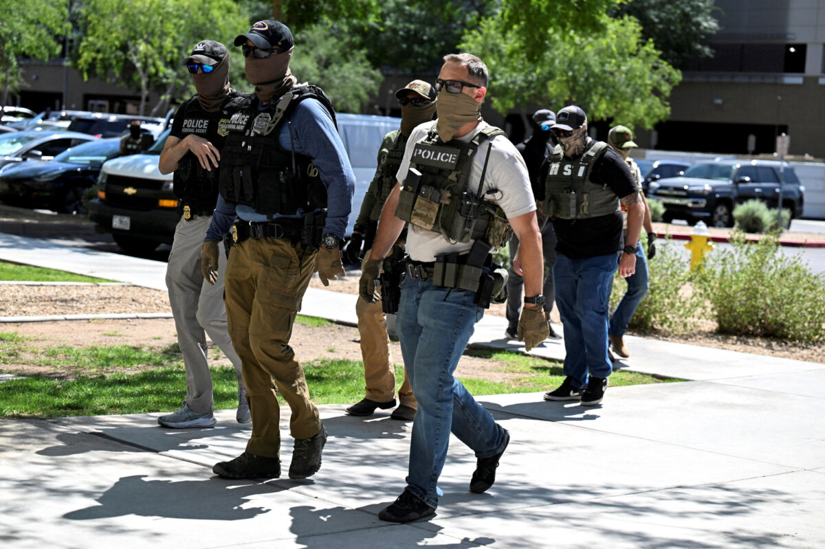Masked law enforcement officers, including HSI and ICE agents, walk into an immigration court in Phoenix, Ariz., on May 21, 2025. (Caitlin O'Hara/Reuters)