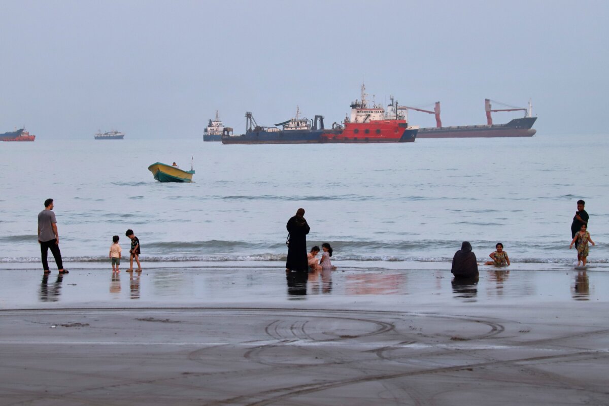People spend time at a beach as commercial vessels are anchored in the Strait of Hormuz off Bandar Abbas, Iran, on Aug. 5, 2026. (Amirhosein Khorgooi/ISNA via AP)