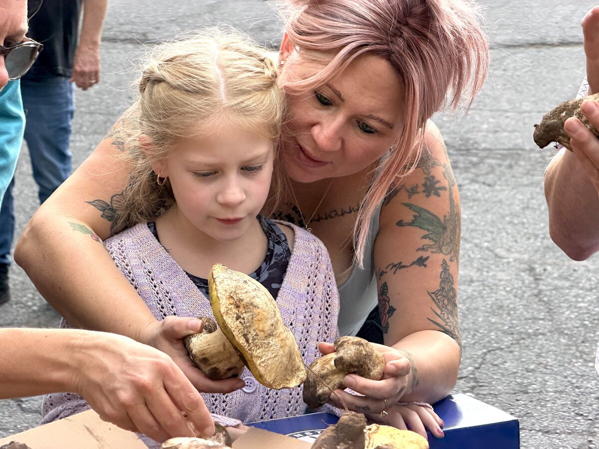 Michelle Lindsay (R) instructs daughter Jovie, 7, in the handling of a wild mushroom during a trip sponsored by the Arizona Mushroom Society in Flagstaff, Ariz., on Aug. 14, 2026. (Allan Stein/The Epoch Times)