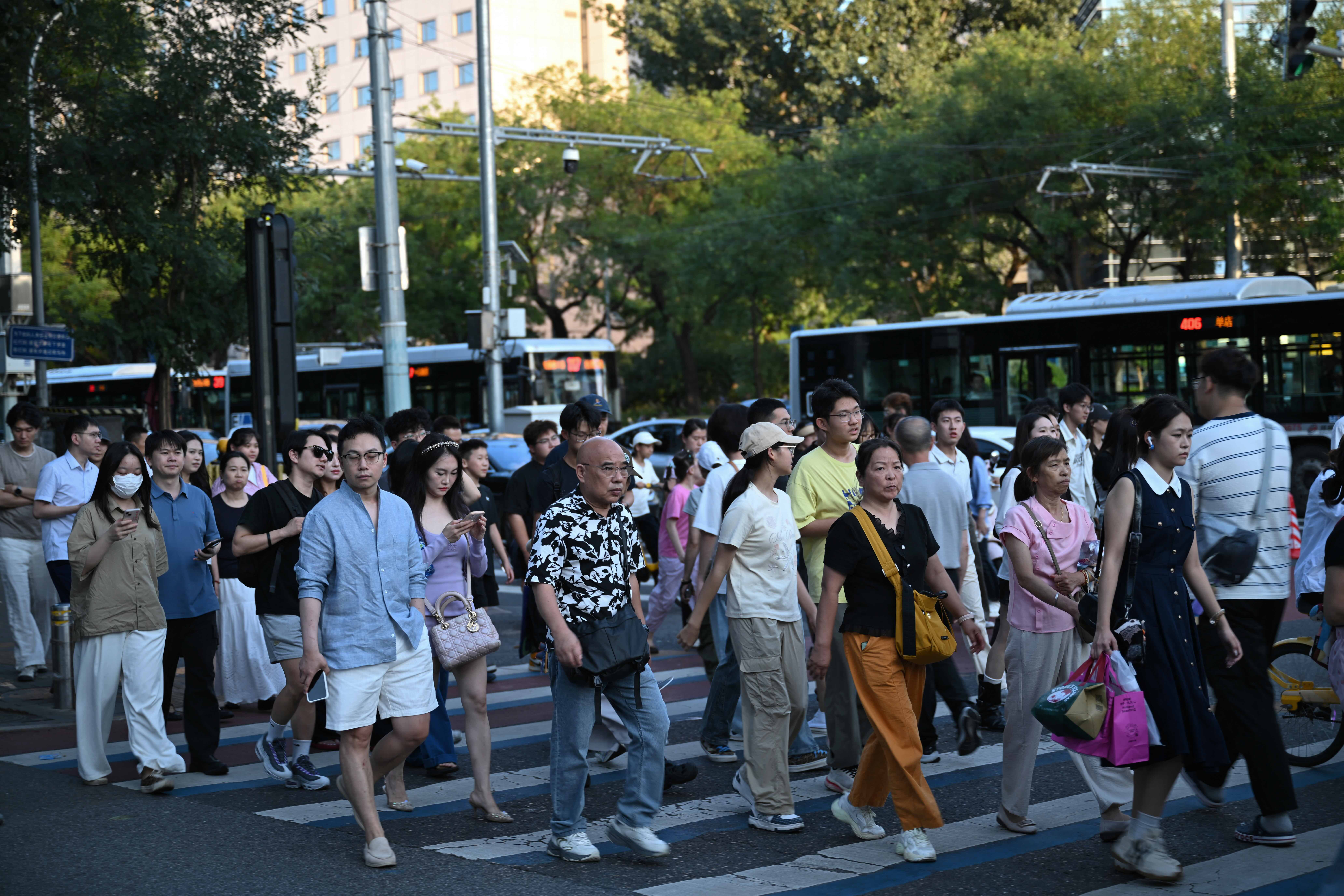 People cross a road in Beijing on August 16, 2026. (Photo by Pedro PARDO / AFP)