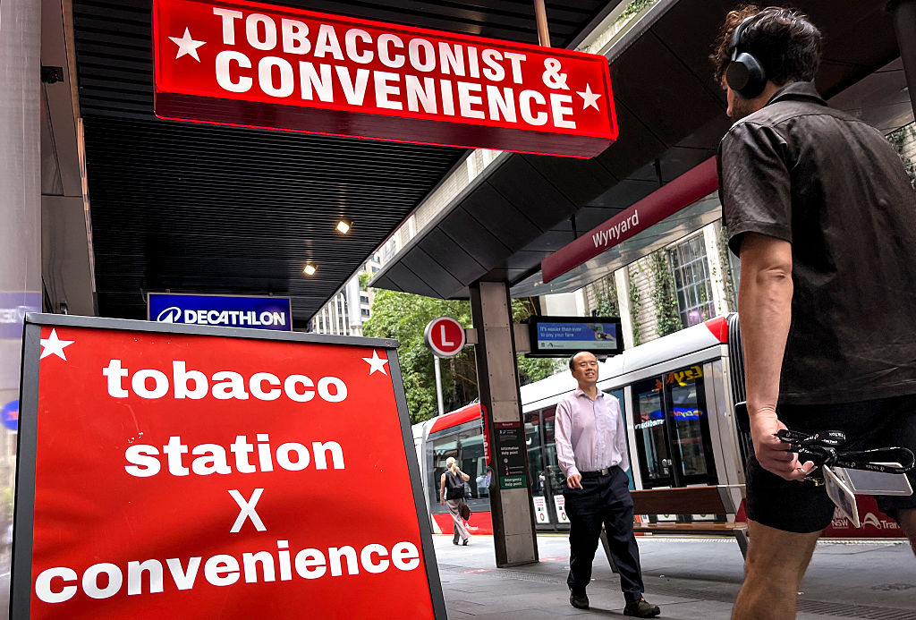 This photo taken on March 27, 2025 shows pedestrians walking past signs outside a tobacconist and convenience store in central Sydney, Australia. (David Gray/AFP via Getty Images)