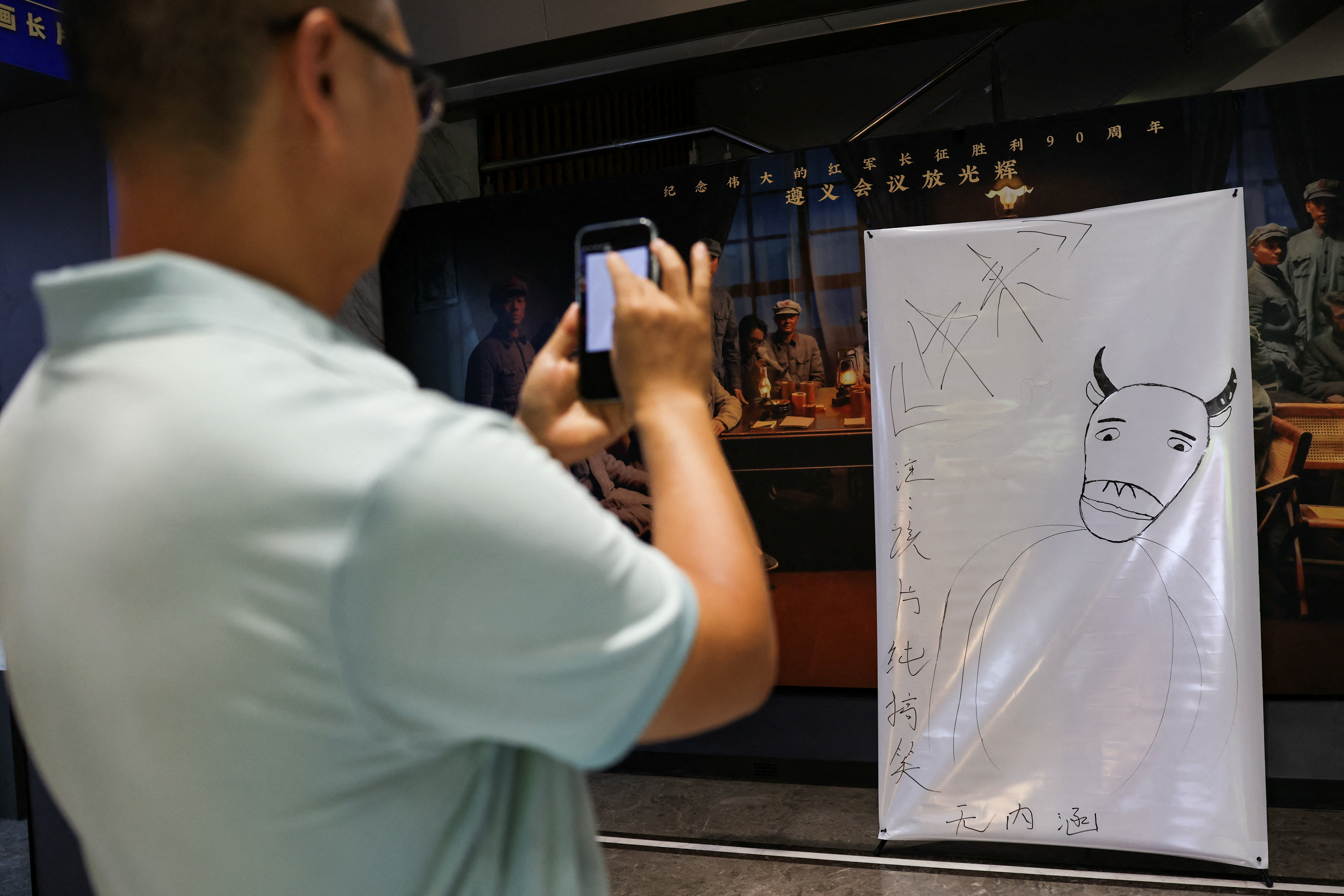 Person checks the back of a hand-drawn poster for the Chinese animated film Niu Lai, at a cinema in Beijing