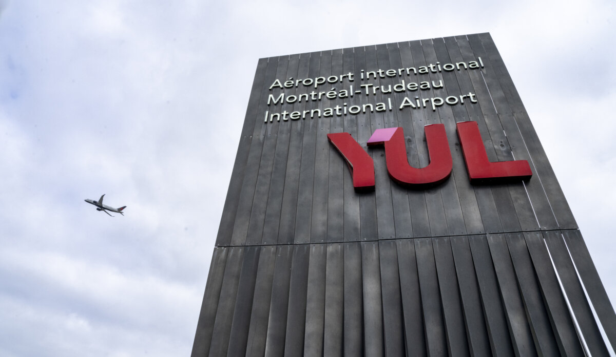A plane flies past a sign for Montreal-Trudeau International Airport in Montreal on Aug. 25, 2026. (The Canadian Press/Christinne Muschi)
