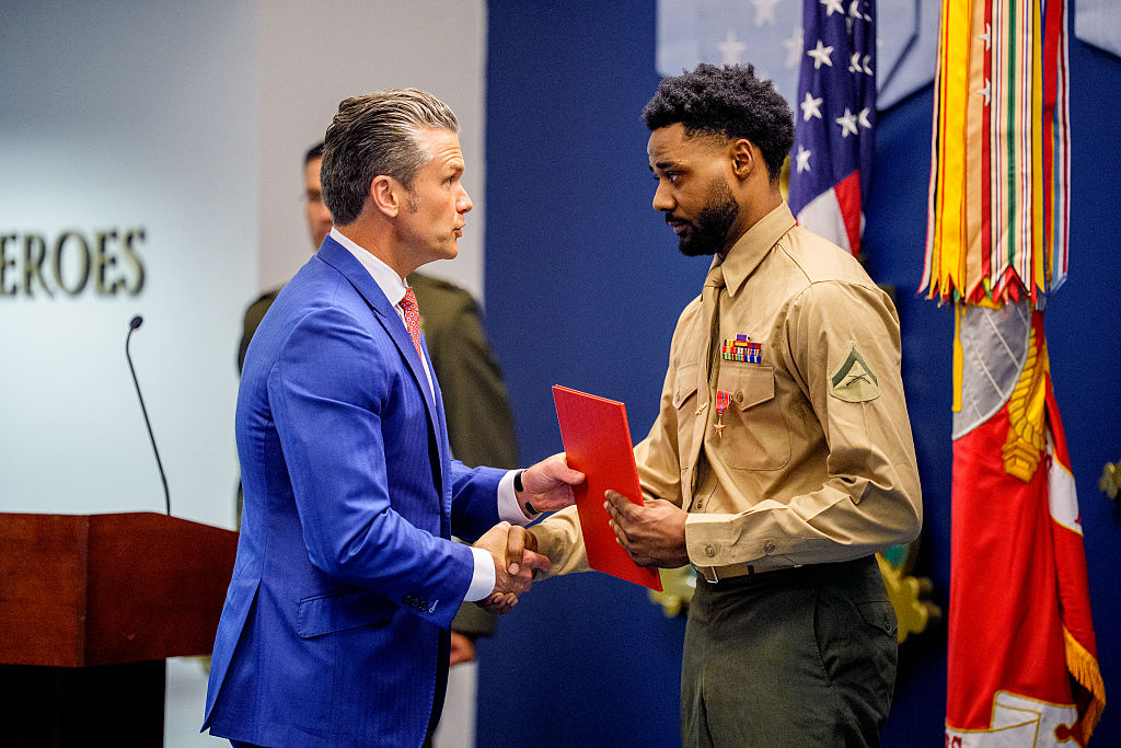 Secretary of War Pete Hegseth (L) shakes hands with Marine Lt. Col. Jordan Houston (R) during an event to honor Marines who were serving during the 2021 Abbey Gate bombing, at the Pentagon in Arlington, Va., on Aug. 26, 2026. Three U.S. Marines from Golf Company have their valor awards formally upgraded to honor their heroism and lifesaving actions during the 2021 Abbey Gate bombing, at Hamid Karzai International Airport in Kabul. (Andrew Harnik/Getty Images)