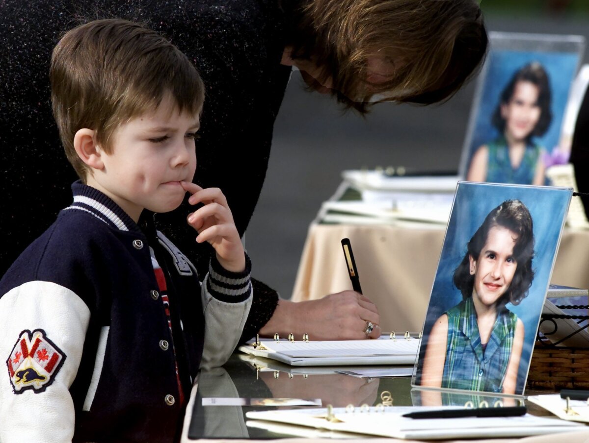 A young boy looks at a picture of Heather Thomas as his mother signs a book of condolence outside a chapel in Surrey, B.C. prior to funeral services for the girl on Nov. 1, 2000. (The Canadian Press/Chuck Stoody)