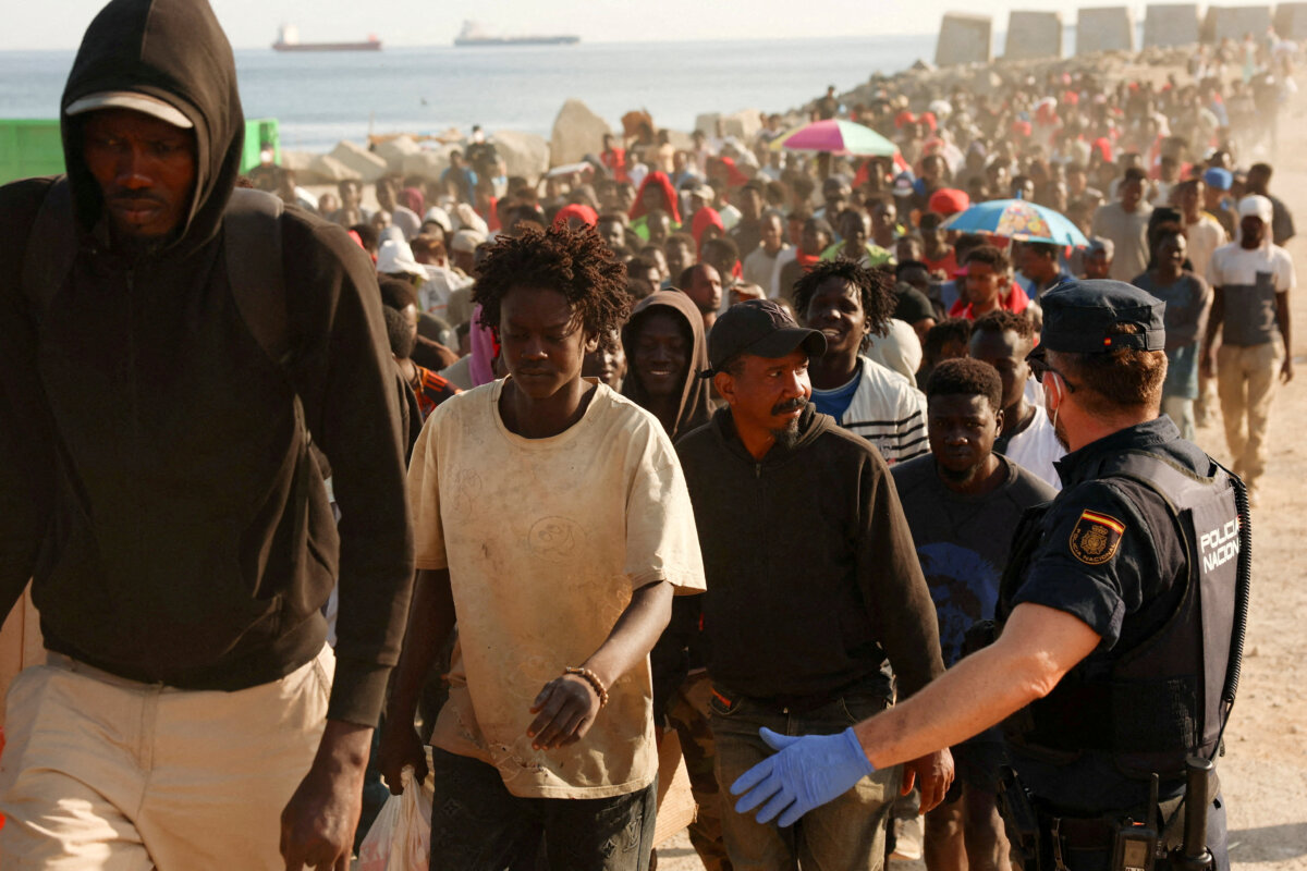Moroccan migrants are escorted from a makeshift beach camp to official shelters across Ceuta after authorities cleared the site in Spain's North African enclave on Aug. 20, 2026. (Violeta Santos Moura/Reuters)