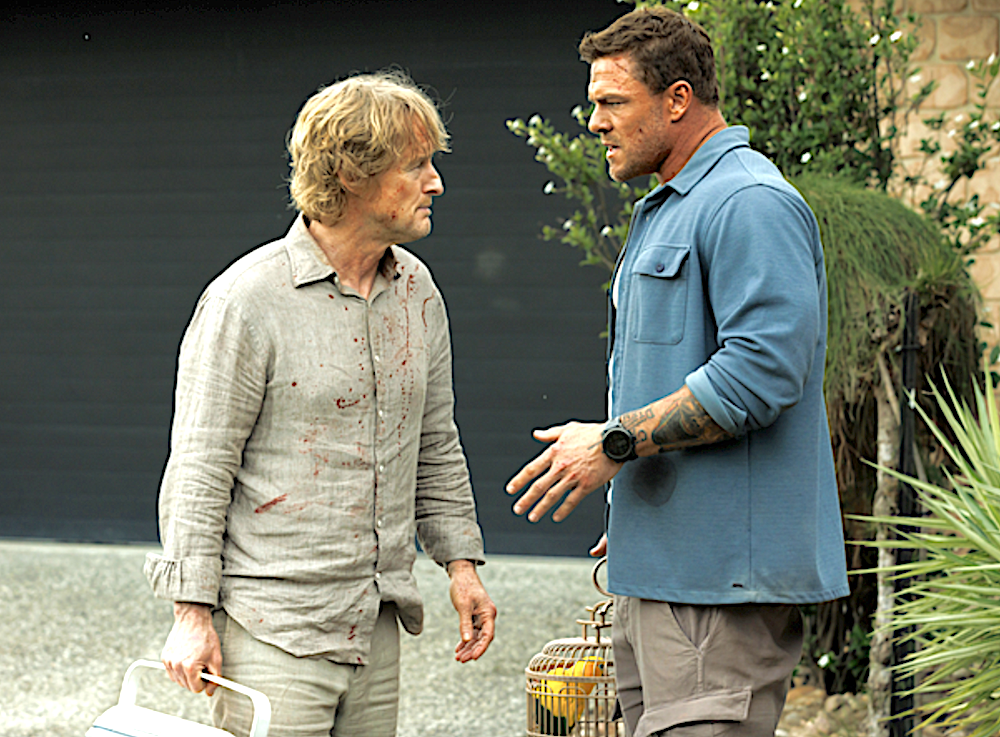 Blond man and man in blue shirt holding a parakeet in a cage in Runner