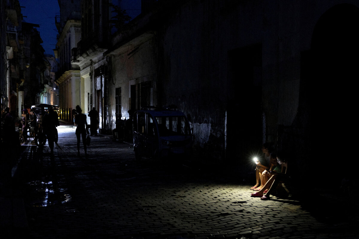 People sit on a darkened street illuminated by a mobile phone flashlight during a power outage in Havana, Cuba, on Sept. 16, 2026. (Ricardo Arduengo/Reuters)