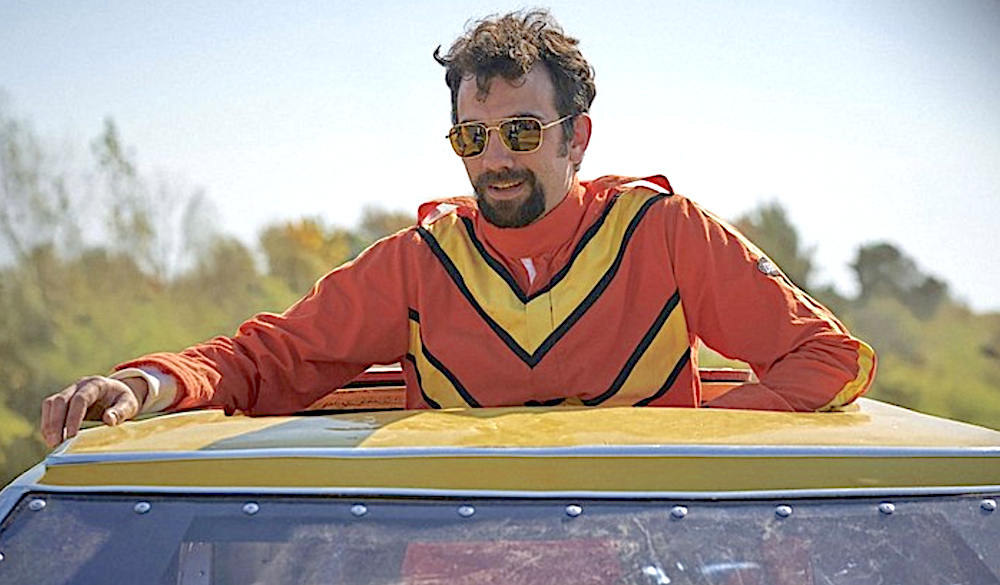man in an orange and yellow fire suit in a yellow care in The Stunt Driver