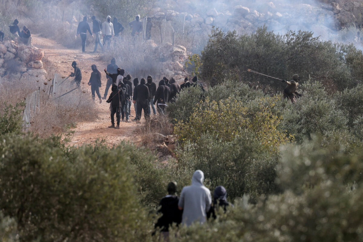 Palestinians look toward Israeli settlers casting projectiles amid clashes during olive harvest in Abu Falah near Ramallah in the Israeli-occupied West Bank, on Oct. 16, 2026. (Ammar Awad/Reuters)