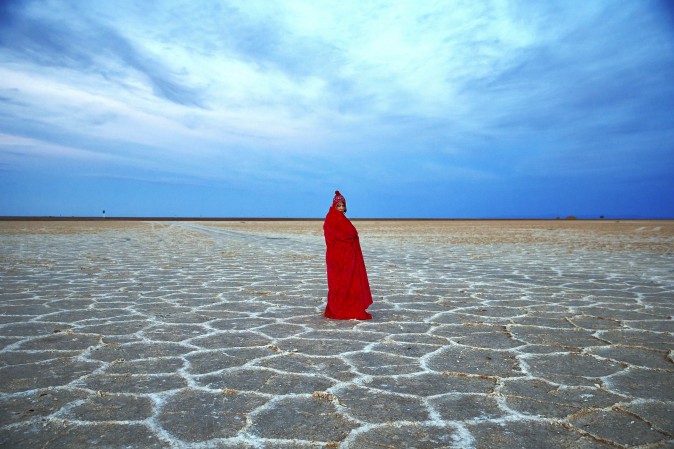 In this picture taken on Thursday, Dec. 1, 2016, an Iranian woman covers herself with a blanket due to the cold, while visiting Khour salt lake during her tour of the Mesr desert in Iran. Deserts make up parts of Iran which have recently become tourist destination for young Iranians looking for a break on their weekend. (AP Photo/Ebrahim Noroozi)