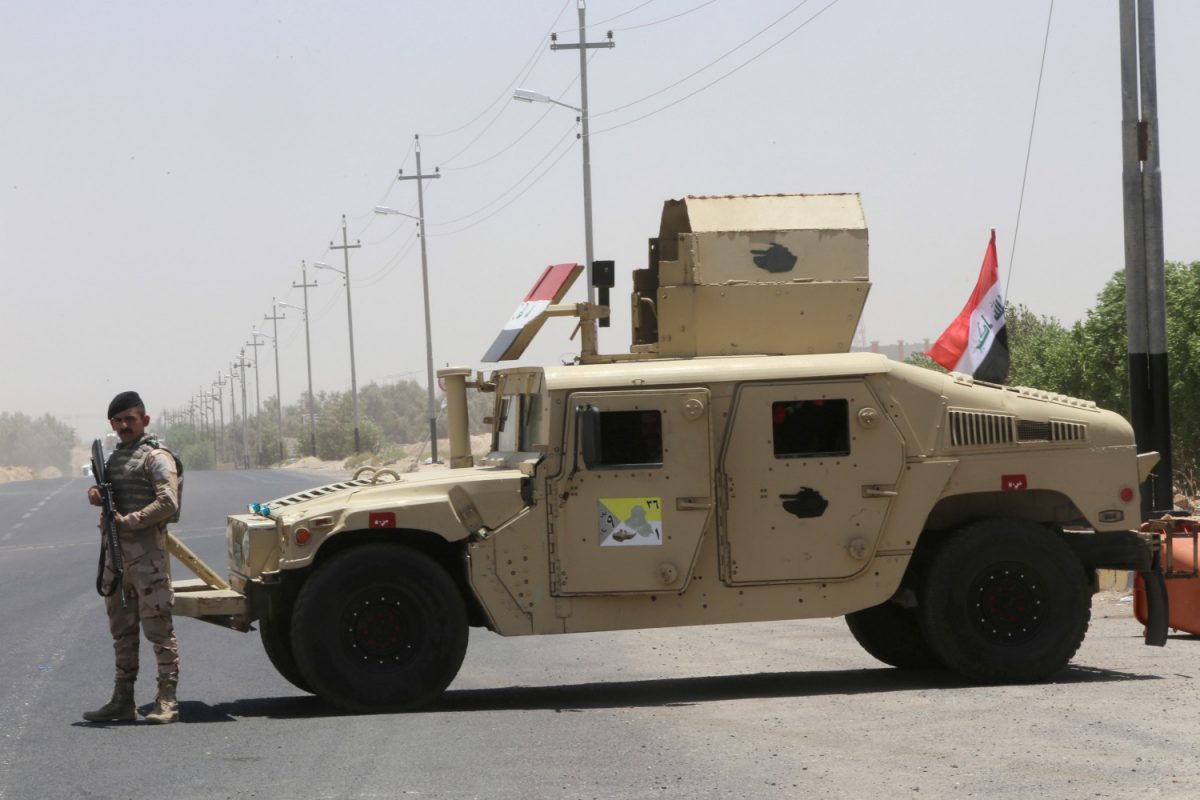 An Iraqi soldier stands next to a military vehicle