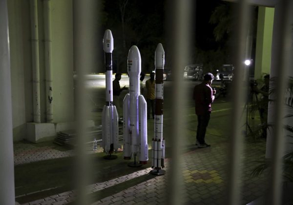 An Indian Video journalist reports standing next to models of Indian Space Research Organization (ISRO)'s Geosynchronous Satellite launch Vehicle