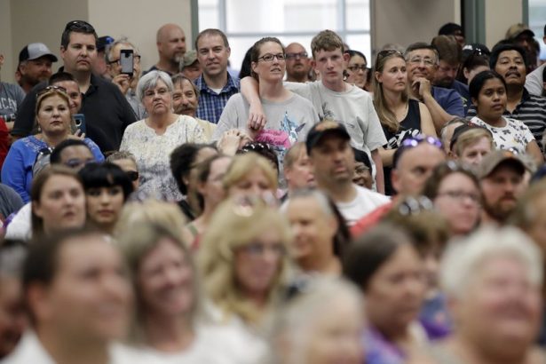 A crowd listens to an official