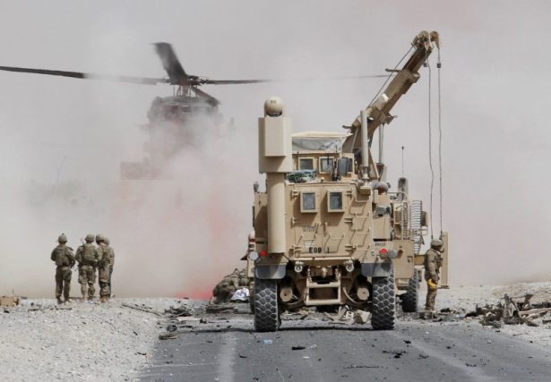 U.S. troops assess the damage to an armoured vehicle of NATO-led military coalition