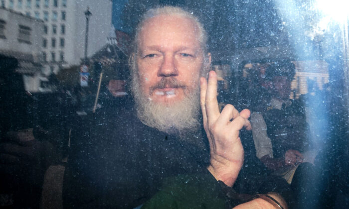 Julian Assange gestures to the media from a police vehicle on his arrival at Westminster Magistrates' Court in London on April 11, 2019. (Jack Taylor/Getty Images)