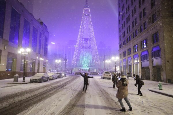 People pose for photos as snow falls